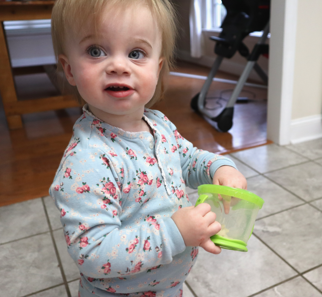 baby holding munchkin snack container